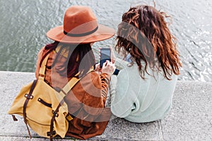 Two women sightseeing Porto views by the river and taking picture with mobile phone. Travel and friendship concept