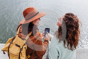 Two women sightseeing Porto views by the river and taking picture with mobile phone. Travel and friendship concept