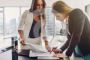 Two women signing a contract standing in modern appartment