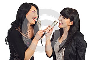 Two women singing to microphones