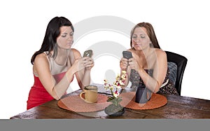 Two women sitting coffee cell phones