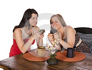 Two women sitting coffee cell phones