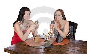 Two women sitting coffee cell phones