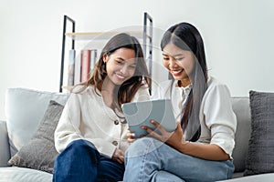 Two women sitting on a couch, one of them holding a tablet