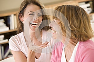 Two women sitting in living room talking and laugh