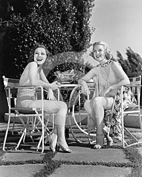 Two women sitting together in a back yard photo