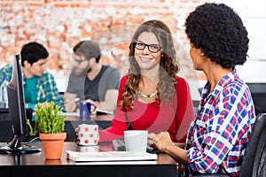 Two Women sitting working office desk computer, business