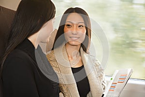 Two Women Smiling and Talking on a Train