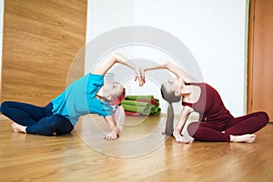 Two women in sportswear doing stretching exercises on yoga mat. Healthy living and fitness concept