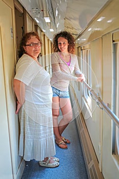 Two women stand in corridor inside train