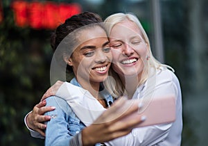 Two women on street taking self portrait. Focus is on women face Memories