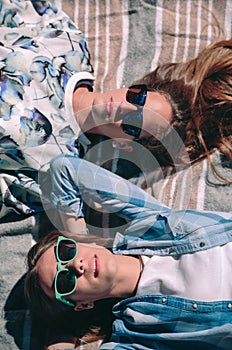 Two women with sunglasses lying taking a sunbath