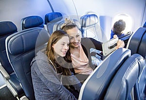 Two women taking a selfie together while traveling on an airplane