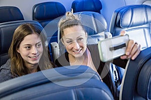 Two women taking a selfie together while traveling on an airplane