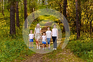 Two women and three children walk through the forest, holding hands. in full growth summer