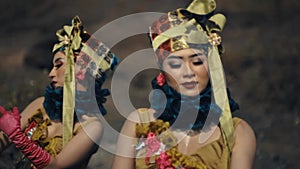 Two women in traditional Asian costumes with elaborate headpieces performing a cultural dance
