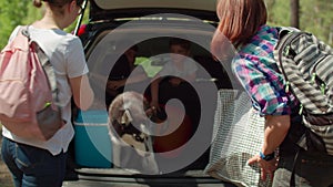 Two women, two boys having and Siberian Husky dog on summer camping vacation. Happy family of two mothers and two sons