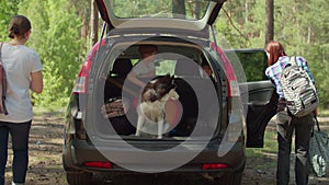 Two women, two boys having and Siberian Husky dog on summer camping vacation. Happy family of two mothers and two sons