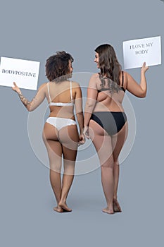 Two women in underwear with posters standing back. photo