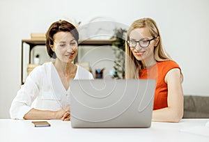 Two women use a laptop