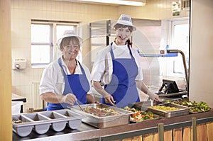 Two women waiting to serve lunch in a school cafeteria