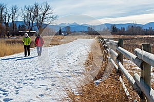 two women walking along a snowy trail on a sunny day