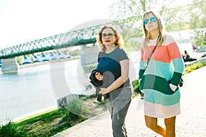 Two women walking along the waterfront - bridge in background