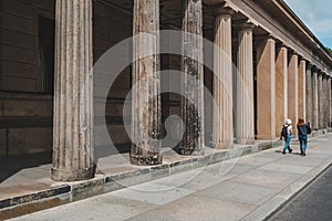 Two women walking by historic columns at the Museum Island in Berlin, Mitte