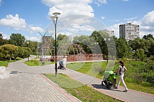 Two women walking with prams in park