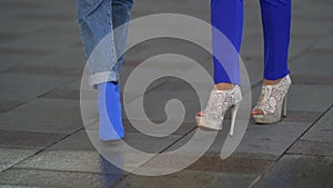 Two women are walking on tiled floor outdoor in city, closeup of feet shod fashion shoes