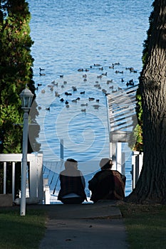 Two women watching the ducks from the dock in Lake Delavan, Wisconsin