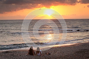 Two women watching the sunrise, sunset from the shore in Nijar, Almeria, Andalusia, Spain