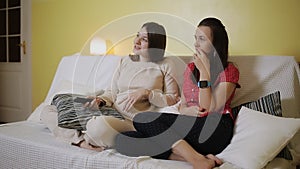 Two women watching television together on the couch at home