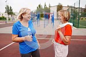Two Women with water bottle smiling. Senior ladies outdoors. New program of aerobic trainings