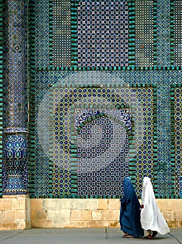 Two women wearing burqas walk past the Blue Mosque in Mazar i Sharif, Afghanistan