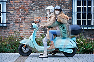 Two women wearing masks and commuting on scooter