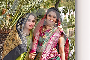 Two women in wedding attire looking at camera, Pune