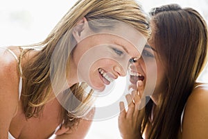 Two women whispering and smiling