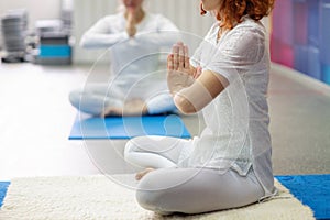 Two women in white clothes is doing kundalini yoga. Pose for meditation