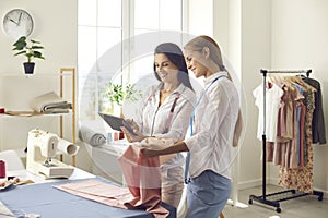 Two women who have a small dressmaking business looking at some designs on a tablet