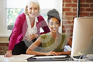 Two Women Working At Computer In Contemporary Office