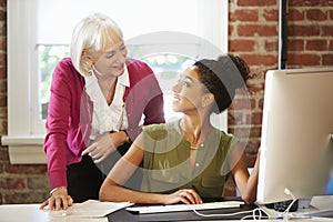 Two Women Working At Computer In Contemporary Office