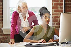 Two Women Working At Computer In Contemporary Office