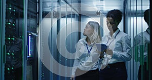 Two women are working in a data center with rows of server racks