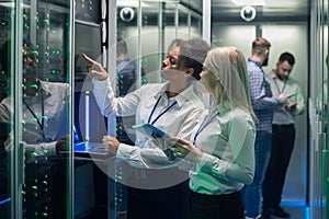 Two women are working in a data center with rows of server racks