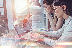 Two women working on new website design choosing pictures using the laptop surfing the internet