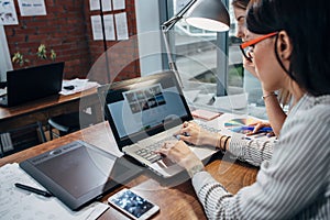 Two women working on new website design choosing pictures using the laptop surfing the internet photo