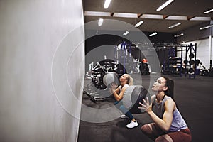Two women working out with medicine balls at the gym