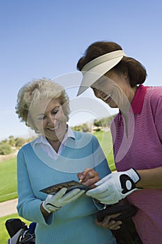 Two women writing in score card on golf course