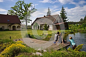 Women and girl sitting by a village house pool